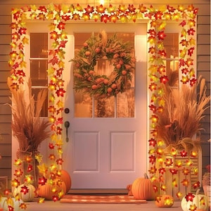 May include: A string of warm white LED lights with orange and red maple leaf-shaped covers. The lights are strung around a white door with a wreath on it. There are pumpkins and fall foliage on the ground.