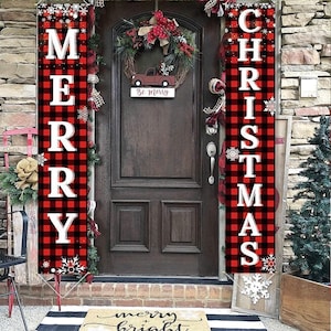 May include: Christmas door decorations featuring red and black buffalo plaid banners with the words "MERRY" and "CHRISTMAS" in white. A wreath with a red truck and the words "Be Merry" hangs on the door.