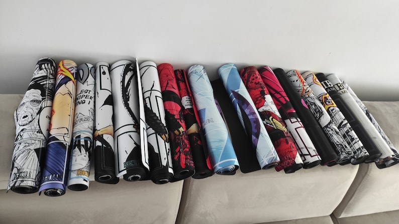 Puede incluir: Una colecci&oacute;n de 15 alfombrillas de rat&oacute;n enrolladas con varios dise&ntilde;os coloridos de c&oacute;mics. Las alfombrillas de rat&oacute;n est&aacute;n dispuestas en un sof&aacute; marr&oacute;n claro.