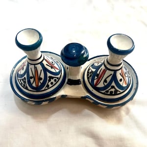 May include: A white ceramic condiment set with two small blue and white patterned dishes with lids. The dishes are attached to a white base with a blue knob in the centre.