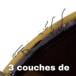 K&ouml;nnte beinhalten: Nahaufnahme des Randes eines gelben und schwarzen Glasobjekts. Der Text "3 couches de verre" ist unten im Bild sichtbar.