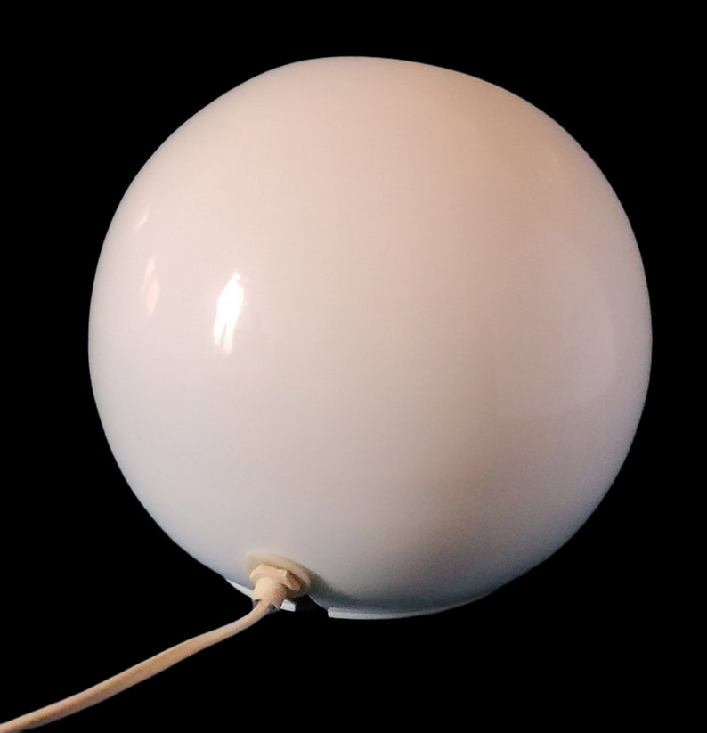 K&ouml;nnte beinhalten: Eine wei&szlig;e Globuslampe mit Kabel und Stecker. Die Lampe ist aus glattem, wei&szlig;em Material gefertigt und hat ein schlichtes, modernes Design.