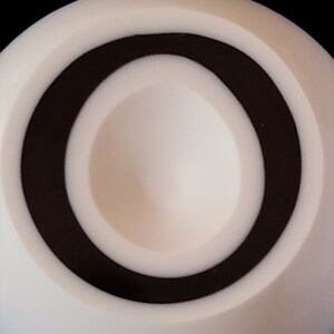 K&ouml;nnte beinhalten: Ein wei&szlig;es kreisf&ouml;rmiges Objekt mit einem schwarzen Ring um die Mitte. Die Mitte hat einen kleinen, vertieften Bereich.