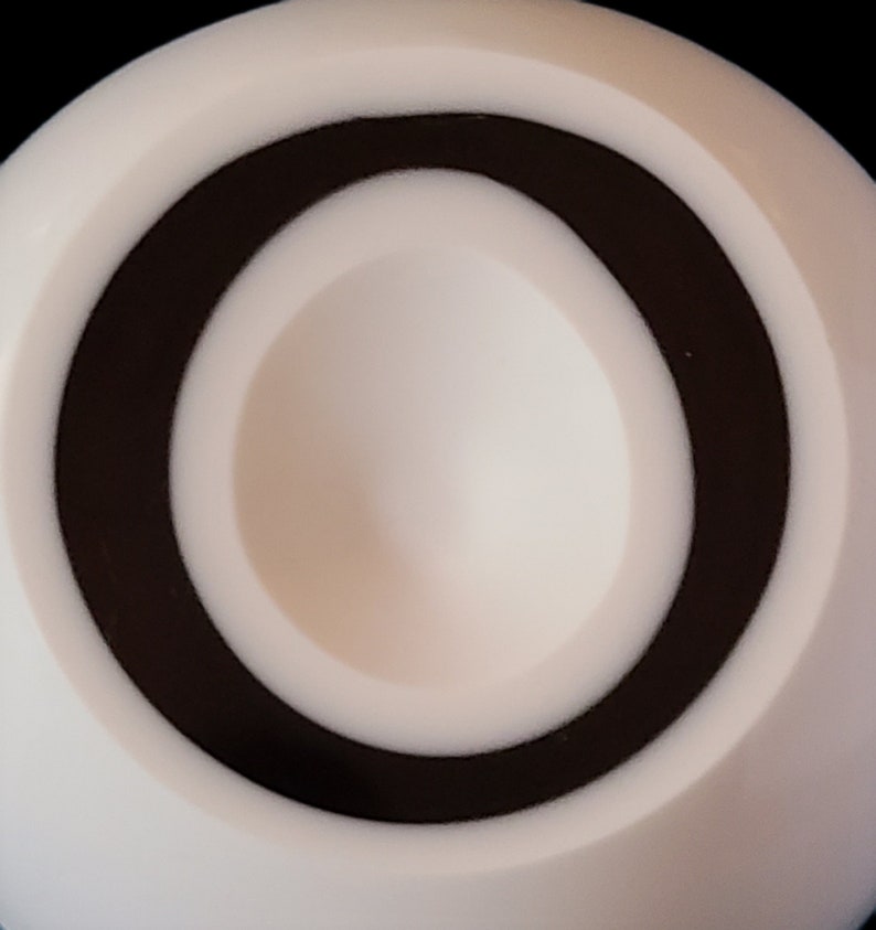 K&ouml;nnte beinhalten: Ein wei&szlig;es kreisf&ouml;rmiges Objekt mit einem schwarzen Ring um die Mitte. Die Mitte hat einen kleinen, vertieften Bereich.