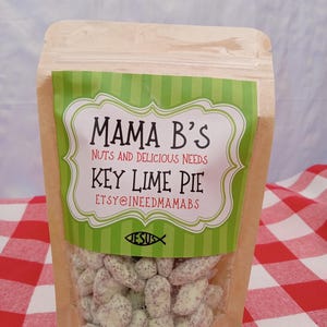 May include: A brown paper bag with a clear plastic window, filled with green and white key lime pie flavored nuts. The bag has a label that reads "Mama B's Nuts and Delicious Needs Key Lime Pie Etsy@ineedmamabs Jesus".
