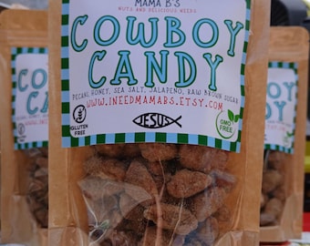 Puede incluir: Bolsa transparente de celofán llena de Cowboy Candy marrón. La bolsa tiene un respaldo de papel marrón con una etiqueta que dice "Cowboy Candy" en letras azules grandes. La etiqueta también enumera los ingredientes y la URL de la tienda Etsy.