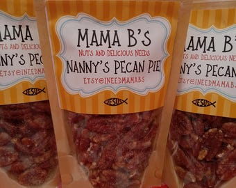 Puede incluir: Tres bolsas marrones de pastel de nueces de pecán con el texto "Mama B's Nuts and Delicious Needs Nanny's Pecan Pie Etsy@ineedmamabs" en la parte delantera de las bolsas. Las bolsas están sobre un mantel a cuadros rojo y blanco.