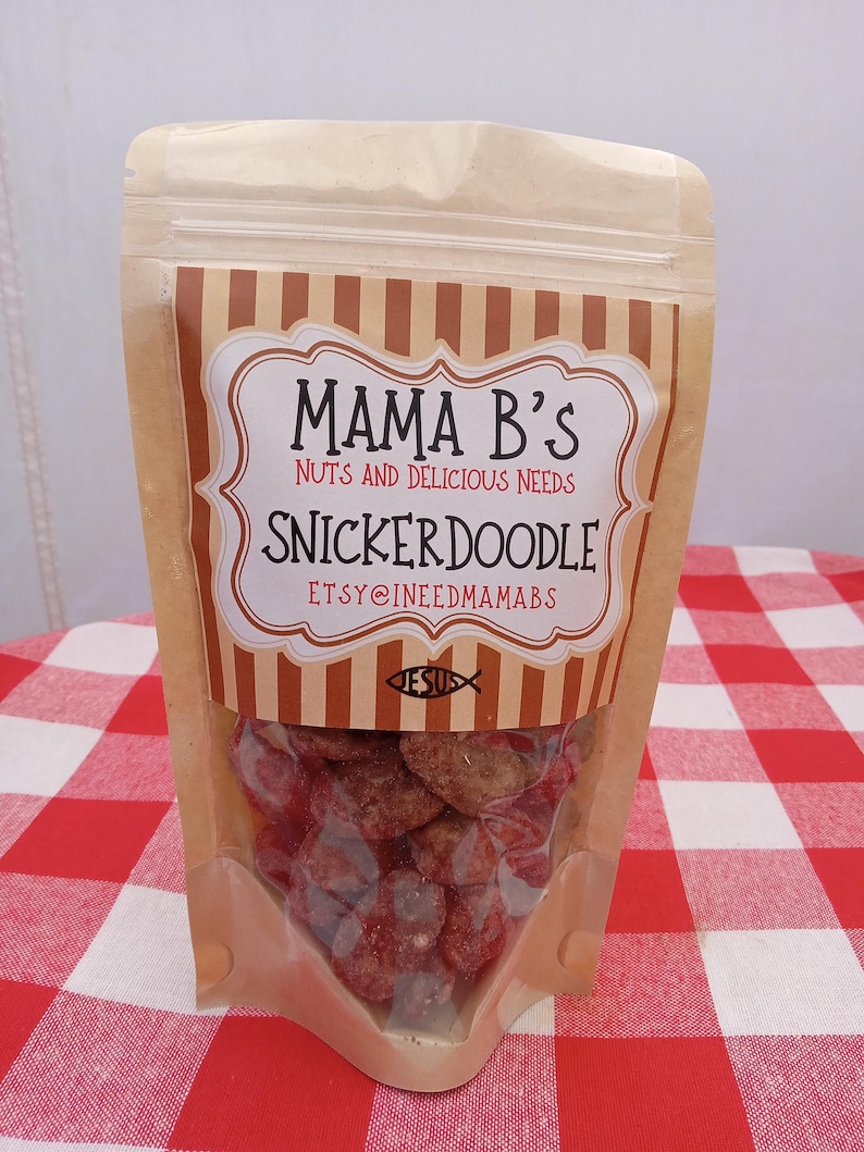 May include: A clear plastic bag filled with Snickerdoodle candies. The bag has a brown and white striped label that reads "Mama B's Nuts and Delicious Needs Snickerdoodle" with the Etsy shop name. The candies are red and brown.