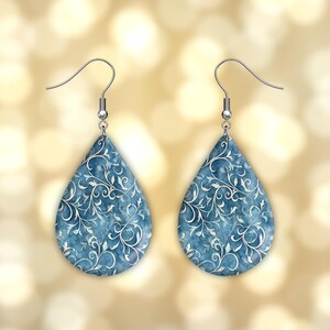 Pu&ograve; includere: Un paio di orecchini a forma di goccia con un motivo floreale blu e bianco. Gli orecchini hanno ganci d'argento.