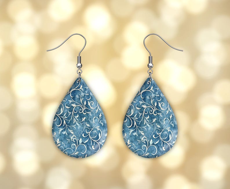 Pu&ograve; includere: Un paio di orecchini a forma di goccia con un motivo floreale blu e bianco. Gli orecchini hanno ganci d'argento.