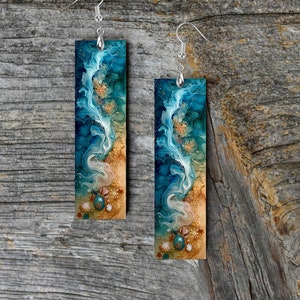 May include: A pair of long, rectangular earrings with a blue and gold abstract design. The earrings feature a swirling pattern reminiscent of ocean waves and seashells.