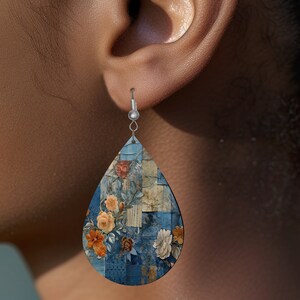 May include: A pair of teardrop-shaped earrings with a blue, orange, and white floral pattern. The earrings are made of wood and have silver hooks.