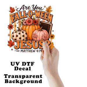 May include: A UV DTF decal featuring the text Are You FALL-O-WEEN JESUS? MATTHEW 4:19. The design includes orange and pink pumpkins, a dark book, autumn leaves, and flowers. The decal has a transparent background and is held up against a white backdrop.