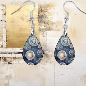 Pu&ograve; includere: Un paio di orecchini a goccia d'argento con un design a motivi blu e bianchi. Il motivo presenta un design ripetitivo di cerchi bianchi con un motivo floreale all'interno.