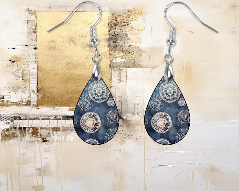 Pu&ograve; includere: Un paio di orecchini a goccia d'argento con un design a motivi blu e bianchi. Il motivo presenta un design ripetitivo di cerchi bianchi con un motivo floreale all'interno.