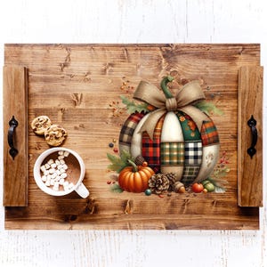 May include: A wooden serving tray with a fall theme. The tray features a decorative pumpkin with a patchwork design, a bow, and autumn foliage. A cup of hot chocolate with marshmallows and cookies are on the tray.