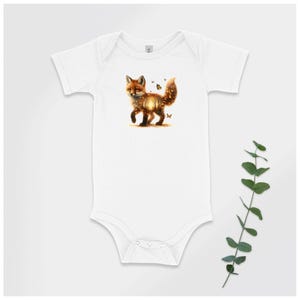 May include: White baby bodysuit with a fox graphic. The fox is depicted with brown and orange fur, and a glowing, detailed design. Small butterflies are scattered around the fox. The bodysuit has short sleeves and a snap closure.
