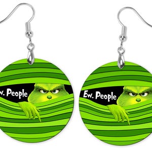 May include: A pair of round earrings with a green and black design. Each earring features a cartoon character peeking through green horizontal lines, with the text "Ew. People". The earrings have silver-colored hooks.