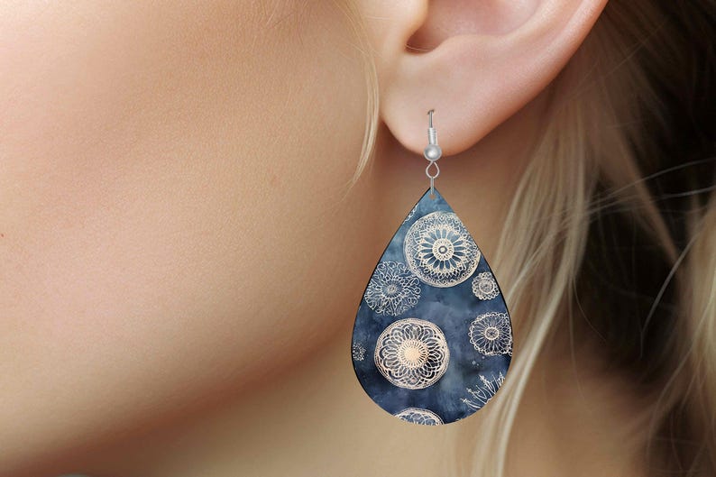 Pu&ograve; includere: Un paio di orecchini a forma di goccia con sfondo blu scuro e un motivo a mandala bianco.