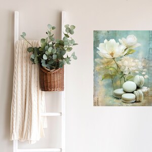May include: A digital painting of white flowers with green leaves on a blue background. There are five light green macarons in the bottom right corner of the image.
