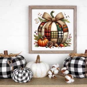 May include: A framed watercolor print of a patchwork pumpkin with a large bow, surrounded by fall foliage.  Three fabric pumpkins in black and white buffalo check, a white pumpkin, and cotton sprigs are arranged on a wooden surface, creating a seasonal display.