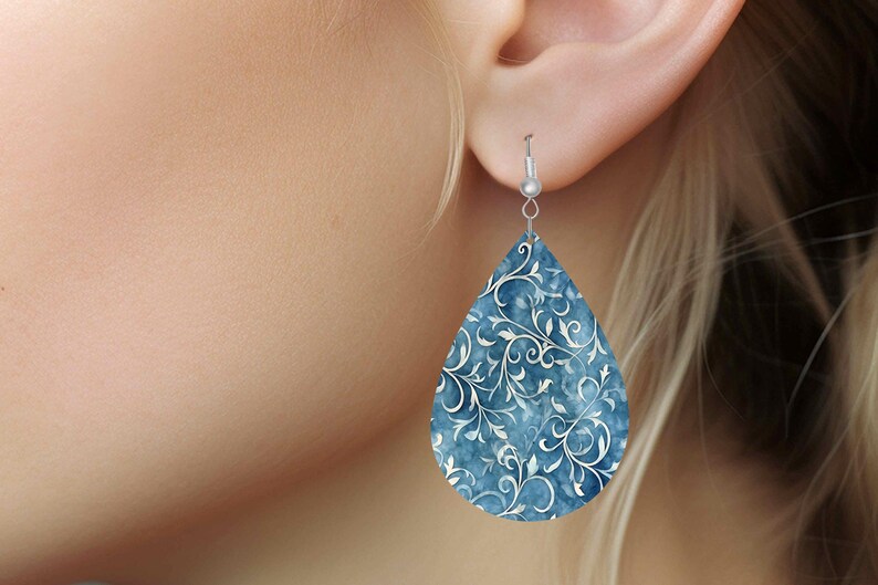 Pu&ograve; includere: Un paio di orecchini a forma di goccia con un motivo floreale blu e bianco. Gli orecchini sono in metallo e hanno una chiusura a gancio argentata.