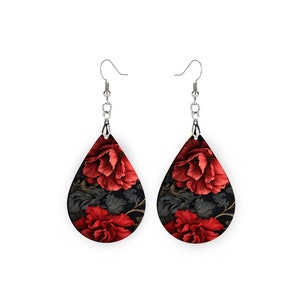 May include: A pair of dangle earrings with a teardrop-shaped design. The earrings feature a black background with red floral patterns.