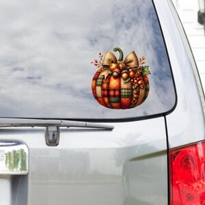 May include: A plaid pumpkin with a brown bow and fall-themed decorations. The pumpkin is on a white car with a window.