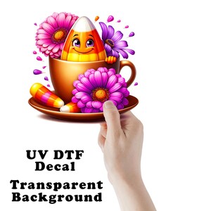 May include: A UV DTF decal featuring a smiling candy corn character inside a brown teacup, surrounded by vibrant pink and purple flowers. Two additional candy corn pieces rest on the saucer. The design includes the text UV DTF Decal Transparent Background.
