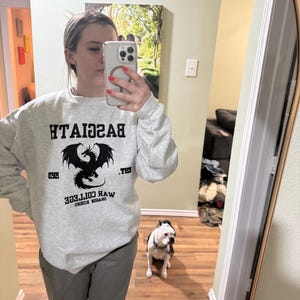 May include: A gray sweatshirt with a black dragon graphic and the text "Dragon Riders War College Est. 2019 Basgiath".