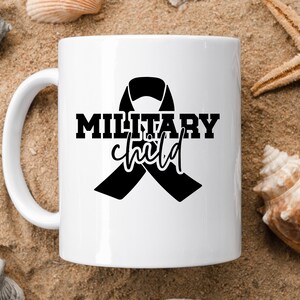 May include: White ceramic mug with a black ribbon and the text "Military child" printed on it.