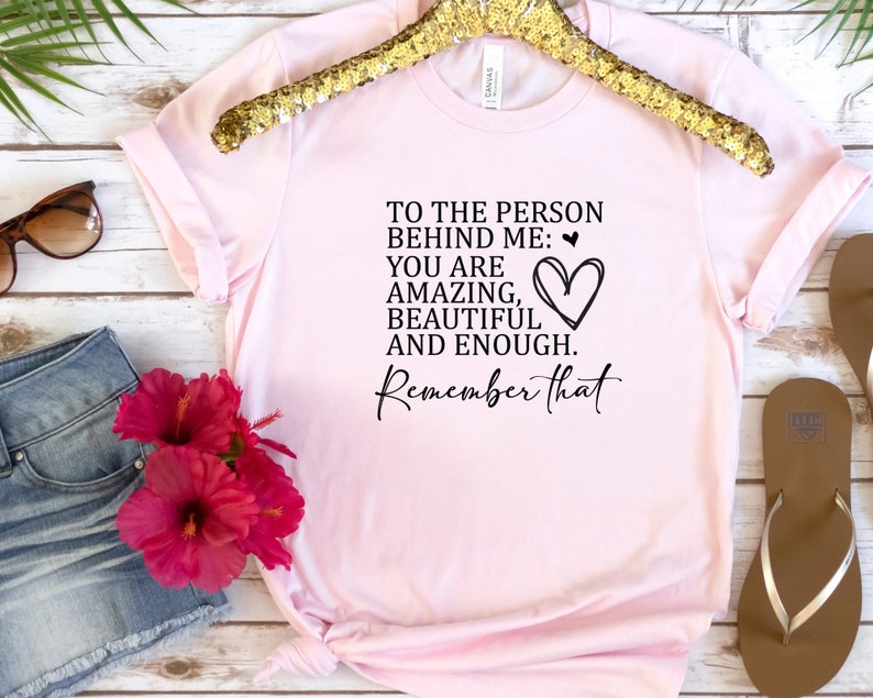 May include: Pink t-shirt with a black graphic that reads "To the person behind me: You are amazing, beautiful and enough. Remember that." with a heart drawn next to the text.