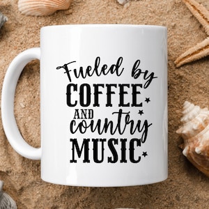 May include: White ceramic coffee mug with black text that reads "Fueled by Coffee and Country Music".