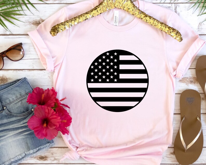 May include: A pink t-shirt featuring a black and white circular design of the American flag.