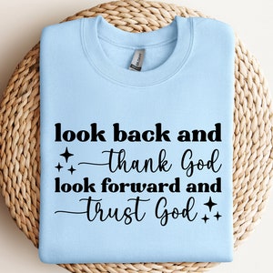 May include: Light blue sweatshirt with the text "look back and thank God look forward and trust God" in black lettering with two small stars on each side of the text.