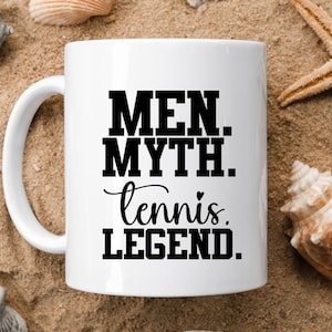 May include: White ceramic coffee mug with black text that reads "Men. Myth. tennis. LEGEND."