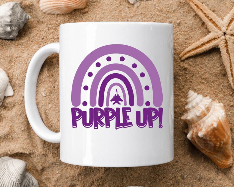 May include: White ceramic mug featuring a purple rainbow design with the text "PURPLE UP!" printed on it. A small purple airplane is flying through the rainbow.