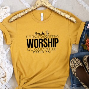 May include: A mustard yellow t-shirt with black text that reads "made to worship" and "PSALM 95:1".