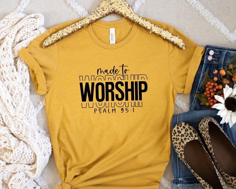 May include: A mustard yellow t-shirt with black text that reads "made to worship" and "PSALM 95:1".