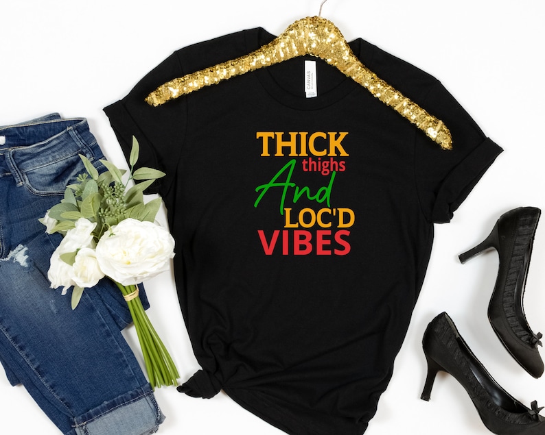 May include: Black t-shirt with the text "THICK thighs And LOC'D VIBES" in green, red, and yellow lettering.