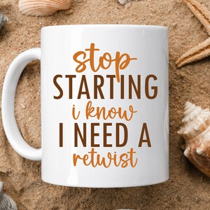 May include: White ceramic mug with a brown and orange design. The mug says "stop starting i know i need a retwist".