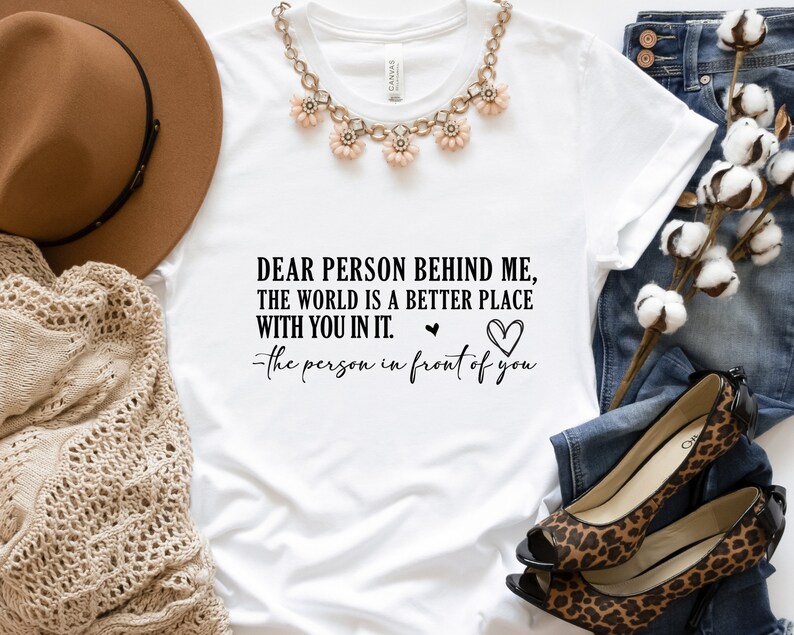 May include: White t-shirt with a black text graphic that reads "Dear person behind me, the world is a better place with you in it. -the person in front of you".