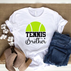 May include: White t-shirt with a green tennis ball graphic and the text "Tennis Brother" in black.