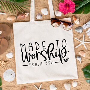 May include: White canvas tote bag featuring the text "MADE TO WORSHIP - PSALM 95:1 -" in black. The bag is surrounded by beach-themed items such as seashells, flip-flops, and palm leaves.