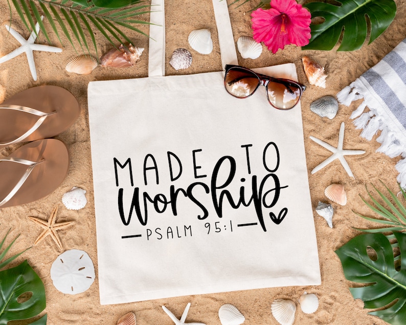 May include: White canvas tote bag featuring the text "MADE TO WORSHIP - PSALM 95:1 -" in black. The bag is surrounded by beach-themed items such as seashells, flip-flops, and palm leaves.
