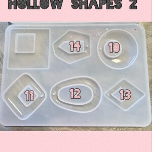 May include: A clear silicone mold with six different hollow shapes for crafting. The shapes are numbered 10 through 14. The mold is on a pink background.