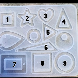 May include: A clear silicone mold with nine different hollow shapes, numbered 1 through 9. The shapes include a square, star, heart, triangle, teardrop, circle, rectangle, and two more circles.
