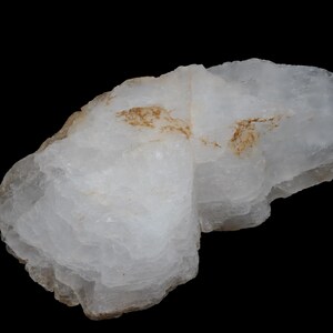 Peut inclure: Une roche blanche et stratifiée avec des stries brunes. La roche a une surface rugueuse et irrégulière.