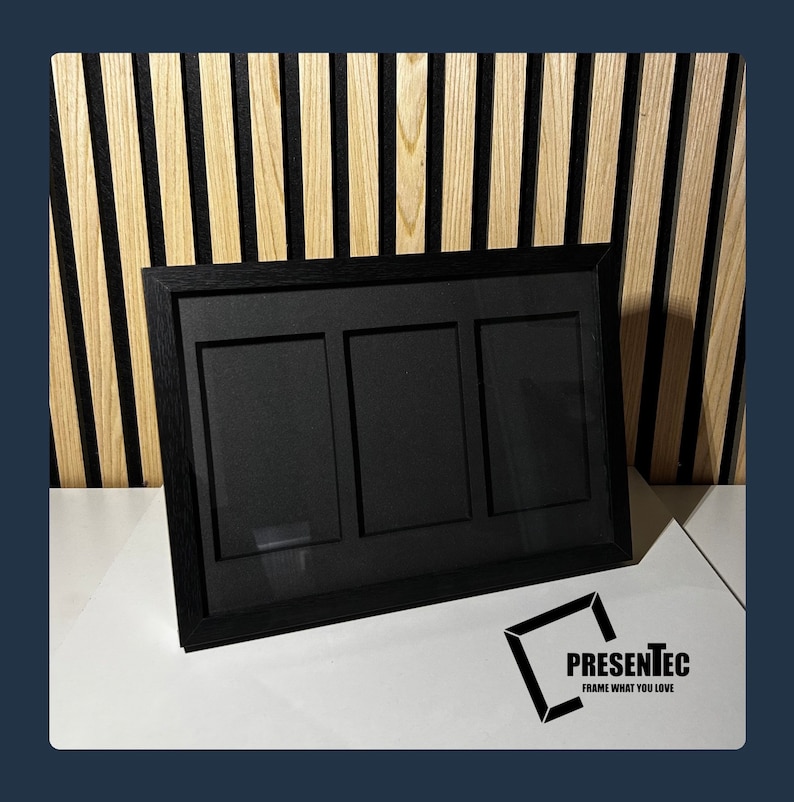 May include: Black triple photo frame with a black mat and a wood grain finish. The frame is on a white surface.