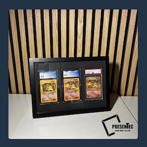 May include: Three Pokemon trading cards are displayed in a black frame with a white mat. The cards are graded 4.5, 9.5, and 9.5. The cards feature the Pokemon Charizard.